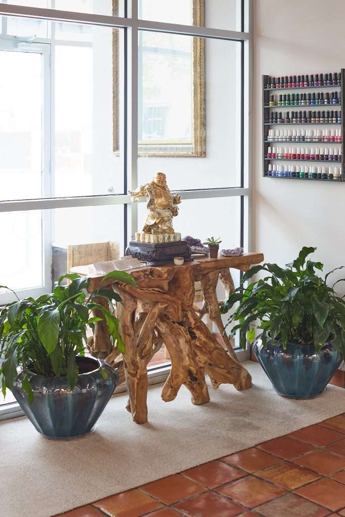 Aurora Spa 5 Golden Buddha on a knotty petrified wood table in the window of Aurora Spa in Minneapolis