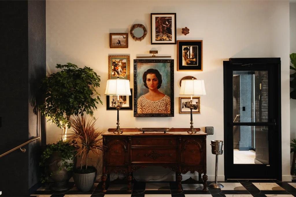Esther's Table: Restaurant Interior Design, Minneapolis 12 Portrait of Esther Capp above an antique carved sideboard with brass lamps, family photographs and layered greenery