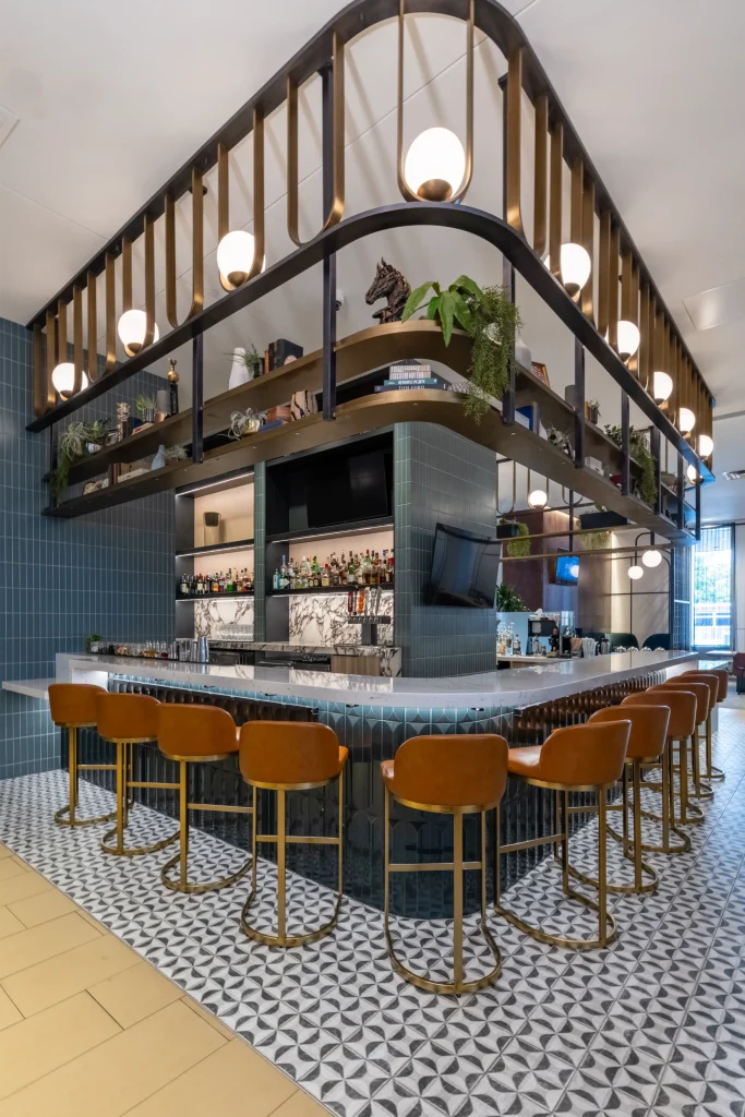 Esther's Table: Bringing a Legendary Minneapolis Hostess Back to the Table 9 Brass bar canopy at Esther's Table styled with trailing greenery, vintage books, a bronze horse sculpture and globe lights