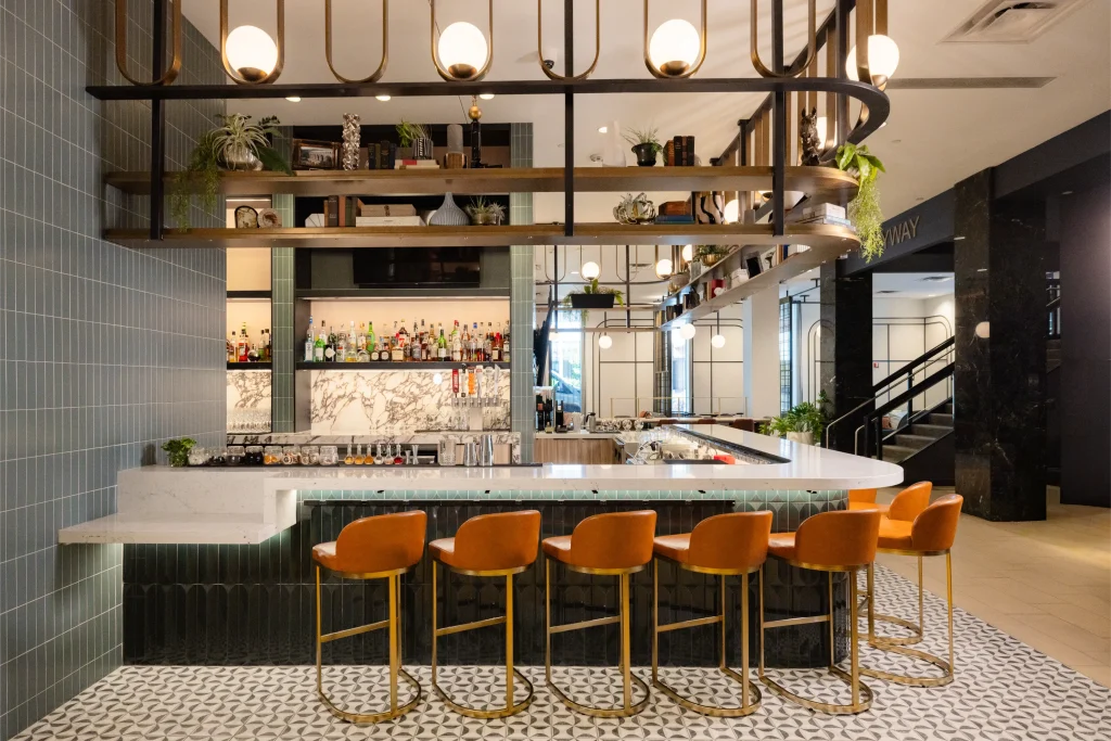 Esther's Table: Restaurant Interior Design, Minneapolis 14 Esther's Table bar with styled brass shelving, globe lighting, marble back bar and skyway access beyond