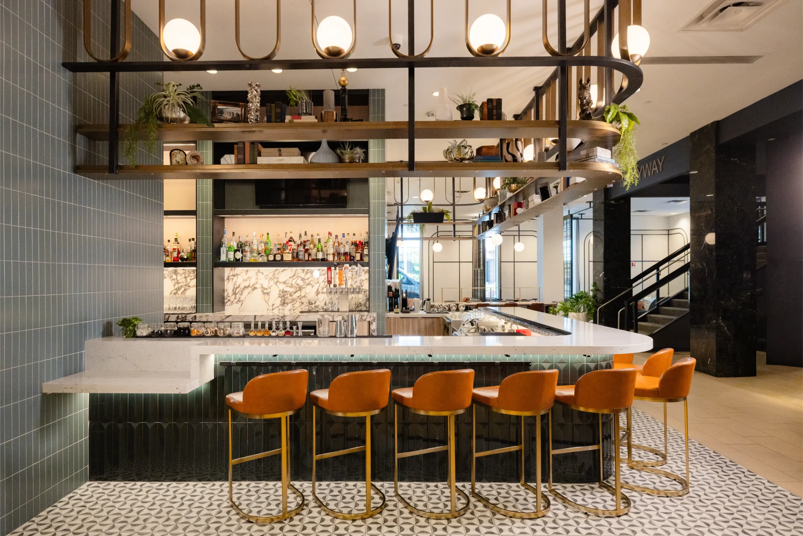 Esther's Table: Bringing a Legendary Minneapolis Hostess Back to the Table 1 Esther's Table bar with styled brass shelving, globe lighting, marble back bar and skyway access beyond