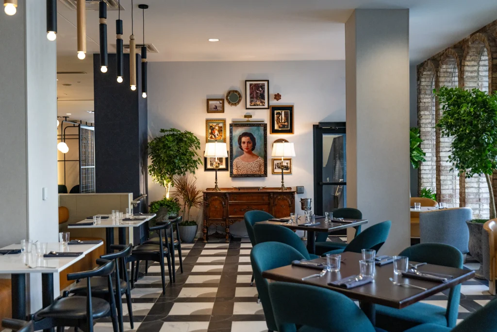 Esther's Table: Restaurant Interior Design, Minneapolis 18 Esther's Table dining room with teal chairs facing a portrait of Esther Capp above an antique sideboard flanked by lamps