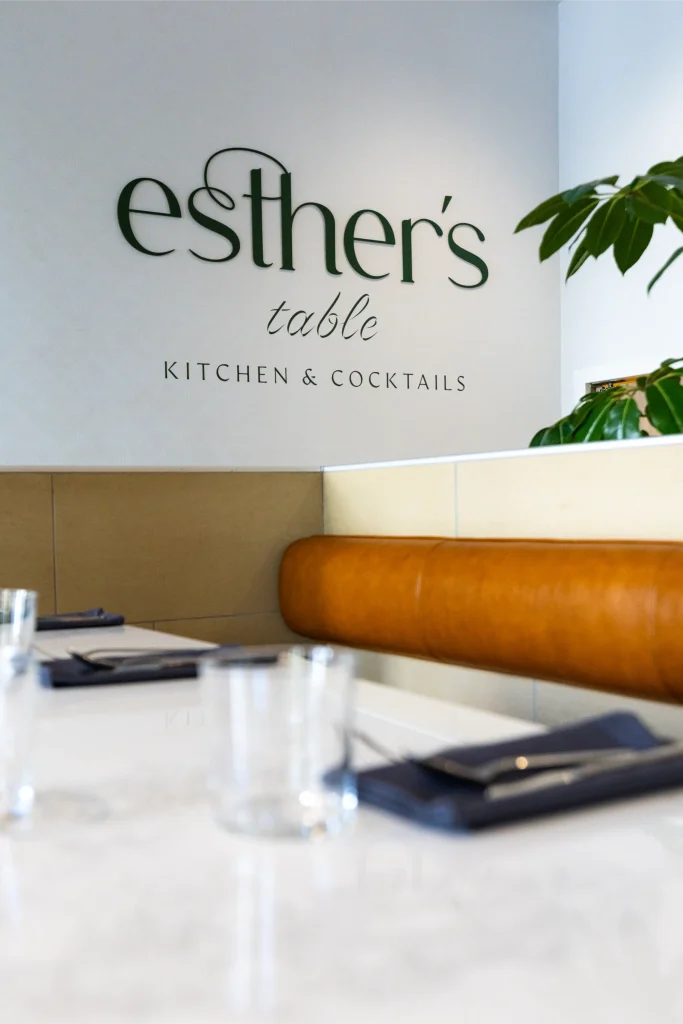 Esther's Table: Restaurant Interior Design, Minneapolis 17 Esther's Table Kitchen & Cocktails signage above a cognac leather banquette and set marble table
