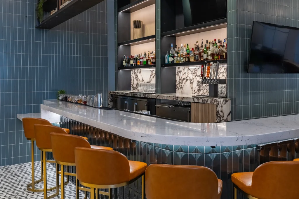 Esther's Table: Restaurant Interior Design, Minneapolis 20 Curved marble bar counter with cognac leather and brass stools, blue tile walls and a backlit marble back bar
