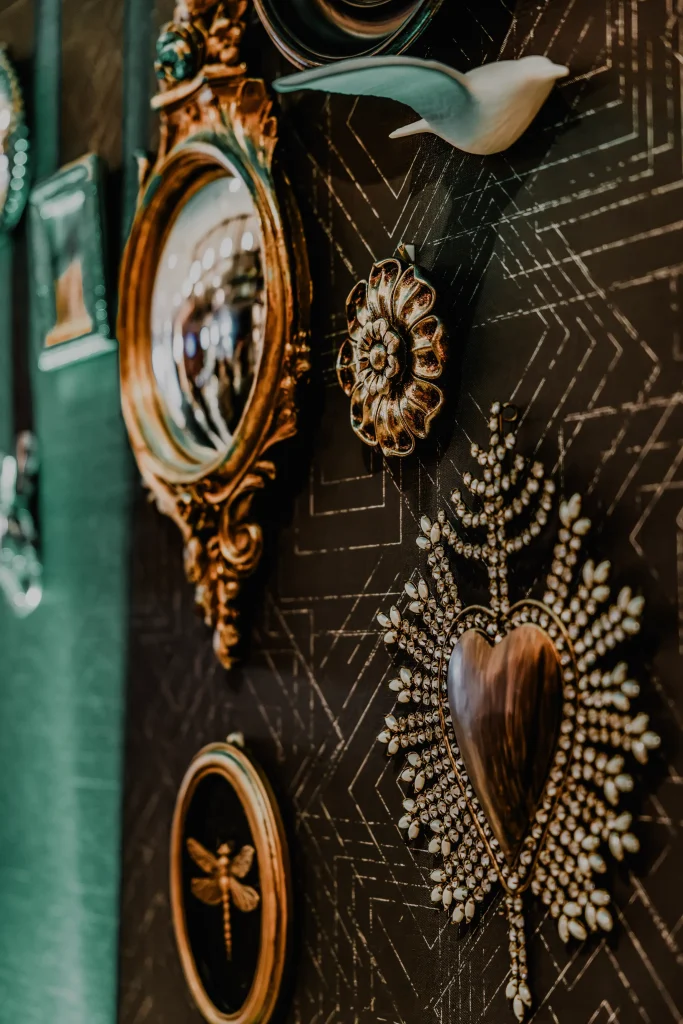 Esther's Table: Restaurant Interior Design, Minneapolis 1 Gilt convex mirror, ceramic bird, brass rosette and pearl starburst brooch on dark geometric wallcovering